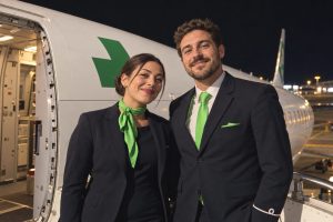 Deux membres d’équipage en uniforme près de la porte d’un avion — illustration avec visages transformés.